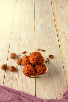 Homemade energy balls with walnuts, peanuts, honey and banana, light wooden surface with a brown napkin on the below. Vegan vegetarian raw snacks. Healthy sweet food. Copy space flat lay, vertical image.