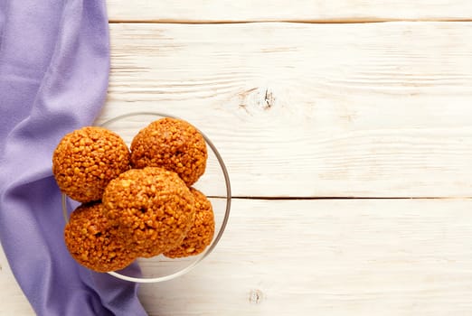 Homemade energy balls with walnuts, peanuts, honey and banana, light wooden surface with a purple napkin on the left. Vegan vegetarian raw snacks. Healthy sweet food. Copy space flat lay, top view.