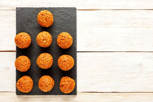 Homemade energy balls with walnuts, peanut, honey and banana on a light wooden table background. Vegan Vegetarian Raw Snacks. Healthy Sweet Food. Copy space. Flat lay, top view.