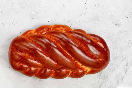 Fresh wicker sweet roll, homemade kalach ruddy on gray concrete background. Top view, copy space.