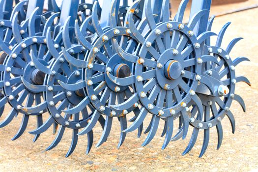 Blue metal toothed harrow as a tow hitch for a tractor for field cultivation, close-up.