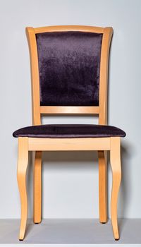 Classic wooden chair with soft dark purple upholstery, photographed frontally, on a gray podium and background.