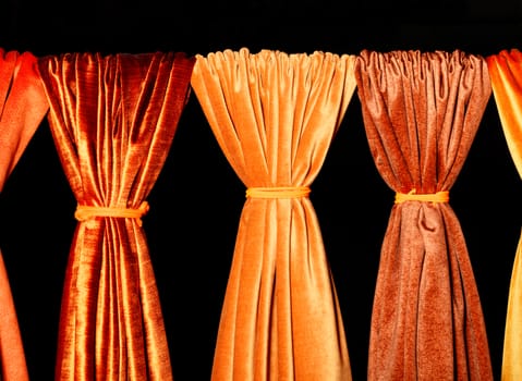 Bright and colorful palette of natural fabrics of gold, orange and yellow shades on a black background. Technology, style and beauty concept in the interior.