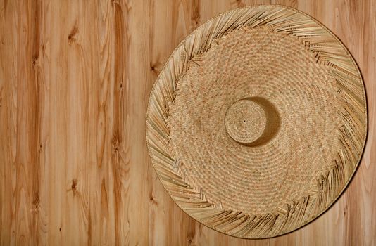 A large beautiful round sambrero hat made of rattan hanging on the background of a natural wooden wall.