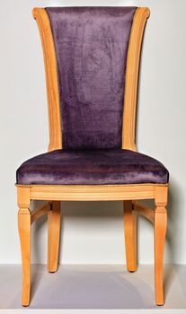 Classic wooden chair with soft dark purple upholstery on saddle and back, photographed frontally, on a gray podium and background.