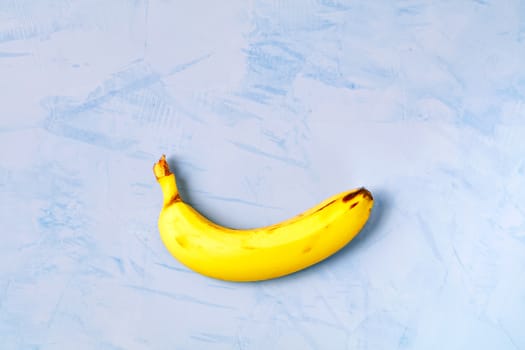 Yellow ripe banana on a dark blue concrete background, flat lay, image with copy space.