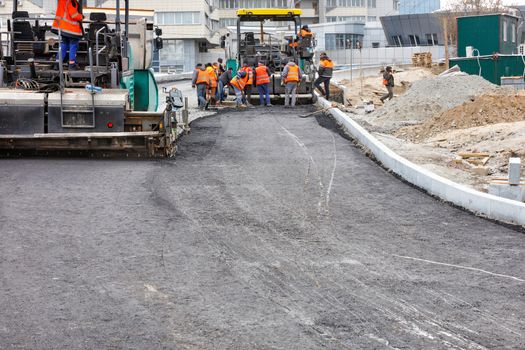 The road team is working with two industrial pavers that apply the first layer of hot asphalt to a new stretch of road, copy space.