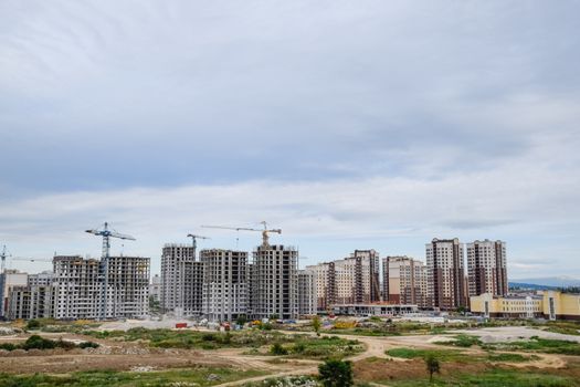 The construction of multi-storey residential buildings. Tower cranes at a construction site.