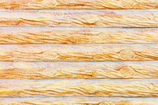 The texture and background of the concrete wall under a stylized wooden fence in the form of horizontal logs in yellow-gold color.