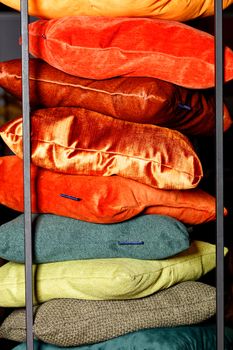 Collection Red, orange, yellow, green, terracotta shades of textile stacks of decorative pillows on a dark background with a metal frame.