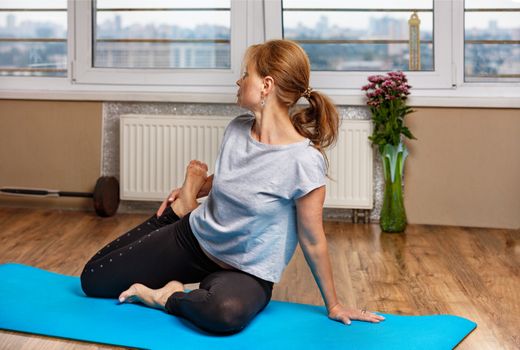 A beautiful middle-aged woman of European appearance does asana bhagti yoga lakshmi narayama at home in her apartment, daily doing fitness for muscle tension.