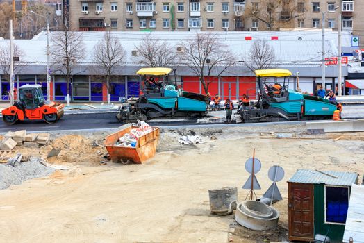 Kyiv, Ukraine, 03/28/2020. Heavy road equipment, such as pavers and a road vibratory roller, are serviced by a road maintenance team to build new transport routes.