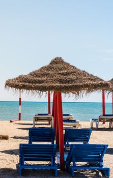 Lonely wicker sun umbrella with two hammocks on empty beach in Fuerteventura. Colorful turquoise sea water on sunny day in Caleta de Fuste, Canary Islands. Nobody enjoying summer holidays concept