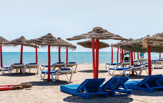 Lonely wicker sun umbrella with two hammocks on empty beach in Fuerteventura. Colorful turquoise sea water on sunny day in Caleta de Fuste, Canary Islands. Nobody enjoying summer holidays concept