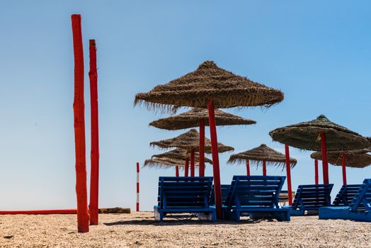 Lonely wicker sun umbrella with two hammocks on empty beach in Fuerteventura. Colorful turquoise sea water on sunny day in Caleta de Fuste, Canary Islands. Nobody enjoying summer holidays concept