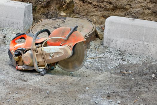 Concrete cutter at a construction site with a running engine and a diamond blade for cutting concrete, copy space.