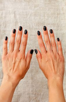 Beautiful female hands with beautiful french manicure nails, beautiful black with shine on beige background in blur, copy space.