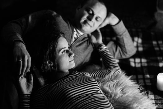 guy and girl are sitting in a wooden house on the background of a burning fireplace