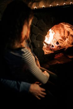 guy and girl are sitting in a wooden house on the background of a burning fireplace