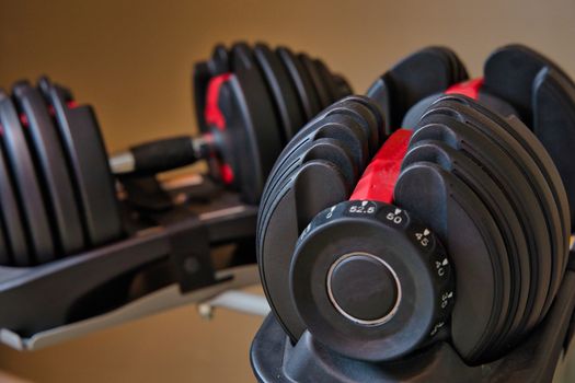 Set of adjustable dumbbells isolated on tan and brown background. Weights for working out at home.