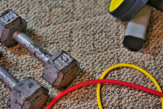 Exercise equipment sitting on carpeted floor of home gym in basement. Workout equipment flat lay with open space