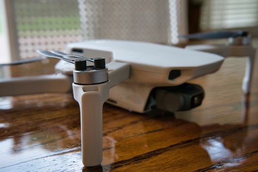 White drone sitting on wooden table. Up close product shot indoors.
