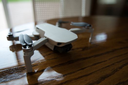 Drone sitting on wooden table inside on sunny day. Door visible in background.
