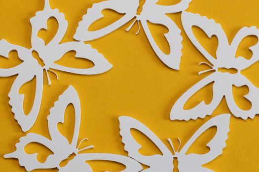 Minimal flatley composition, top view. White butterflies on a yellow background, a creative minimal concept, copy space.