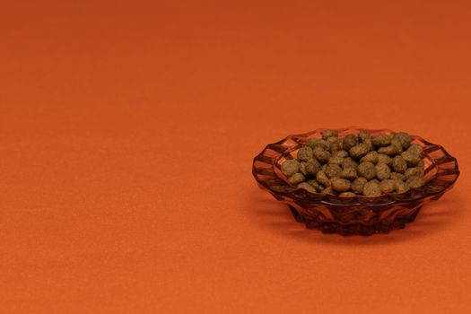 Balls of cat food in a beautiful bowl on an orange background, isolate. The concept of pet food.