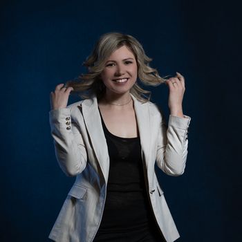 30 years old woman with blond hair in business clothes posing in the studio on a dark background