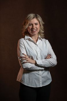 30 years old woman with blond hair in a white shirt posing in the studio on a dark background