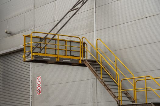 fire safety elements on the wall of an industrial building: stairs, fences, signs