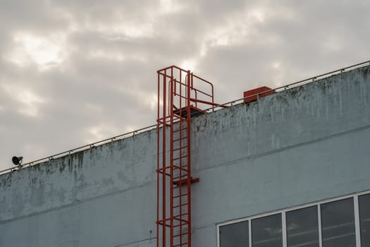 red fire escape leading to the roof of an industrial building