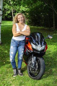 twenty something blond girl, leaning on a sport motocycle
