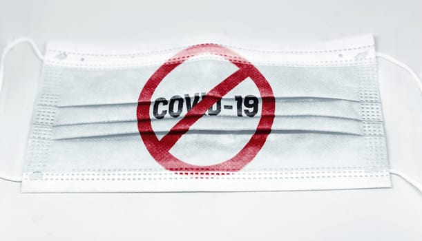 surgical mask with the prohibition red sign to Coronavius covid-19 printed. Pandemic covid-19 and preventive measures to counter the spread of the virus