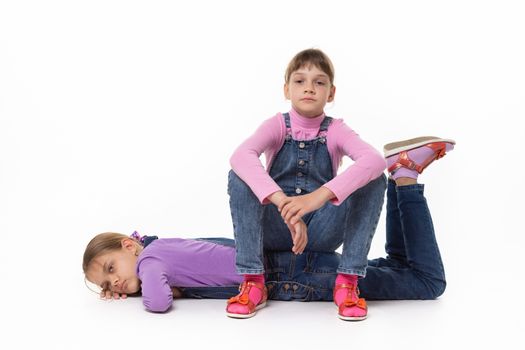 Two sad girls rest sitting and lying on a white background