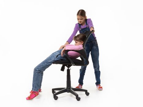 Girl offended by sister sliding off chair on a white background