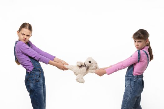 Two disgruntled sisters share a toy on a white background