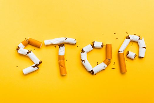 31 May of World No Tobacco Day, no smoking close up word STOP spelled text of the pile cigarette or tobacco on yellow background with copy space, and Warning lung health concept