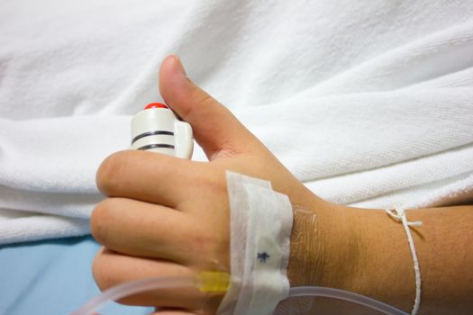 The hand of a patient in hospital holding a help or assist call button in case of emergency or distress.