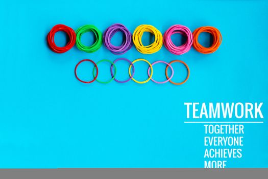 Teamwork concept. group of colorful rubber band on blue background with word Teamwork, Together, Everyone, Achieves and More
