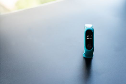fitness smart band device blue color on black background with word Hello healthy