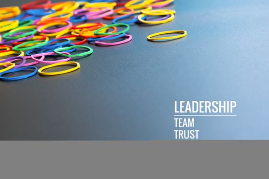 Leadership business concept. yellow color rubber band lead other color with word Leadership, team, trust and respect on black background