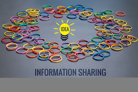 Information sharing concept, colorful rubber band with word Information Sharing and idea lighting bulb on black background