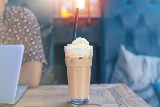 ice mocha coffee on wooden table with working man using laptop