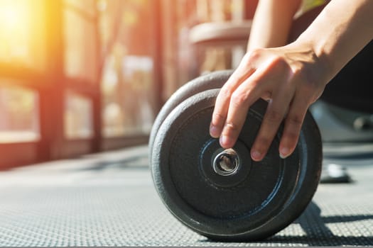 women hand setting the steel dumbbell in a gym musclebuilding