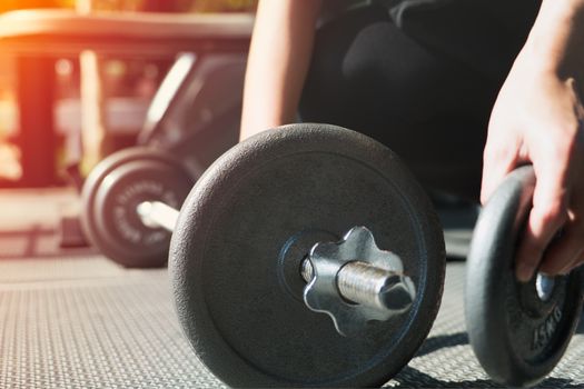 women hand setting the steel dumbbell in a gym musclebuilding