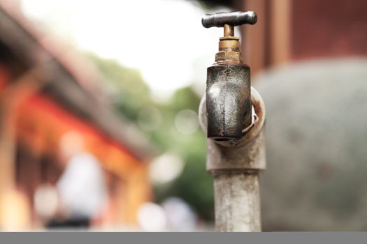 a bronze metallic faucet with water drop on blurred background