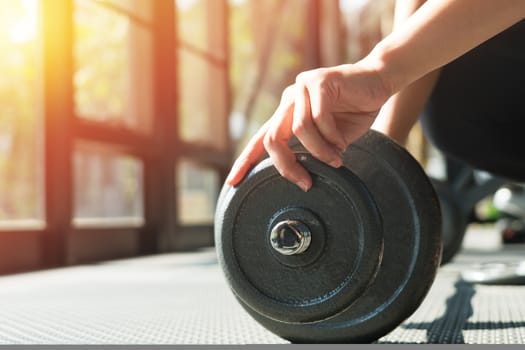 women hand setting the steel dumbbell in a gym musclebuilding