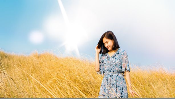 Asia Girl Outdoors enjoying nature. girl in blue dress walking on the Spring Field, Sun Light.
